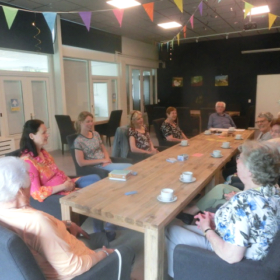 Foto van diverse personen aan een tafel die in gesprek zijn met elkaar.