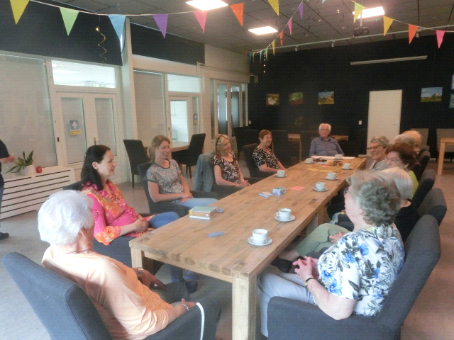 Foto van diverse personen aan een tafel die in gesprek zijn met elkaar.