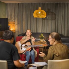 Foto van mensen en een vrouw met een gitaar