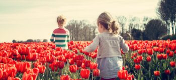 Foto van 2 kinderen in een veld van rode tulpen