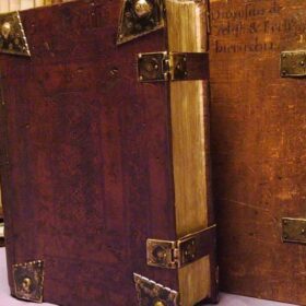 Foto van een rechtopstaand oud boek met bruine kaft.