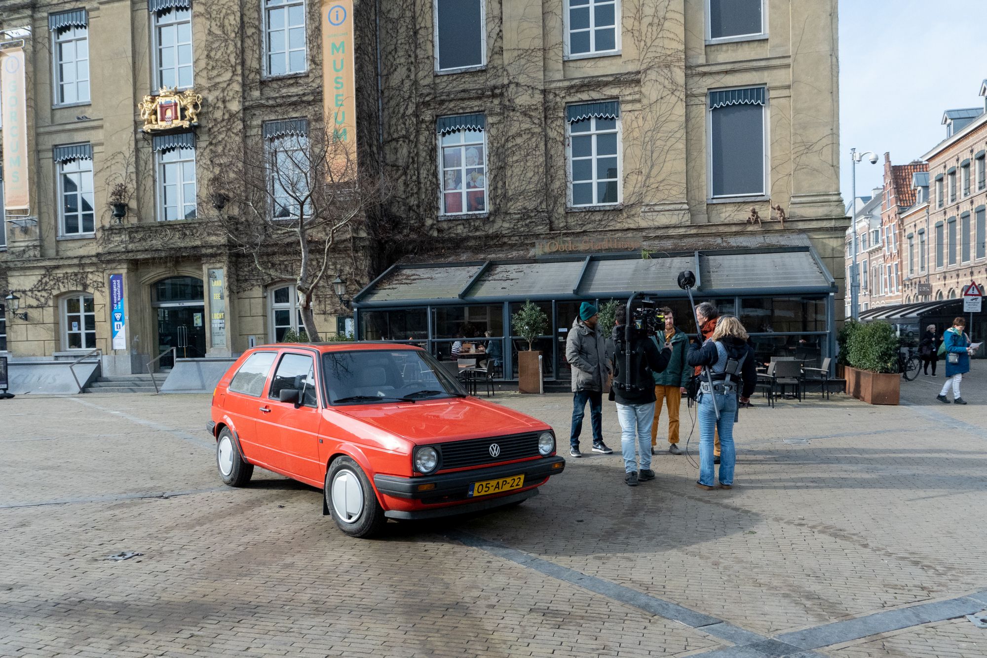 foto van rode auto met boom uit het dak op plein voor het Gorcums Museum