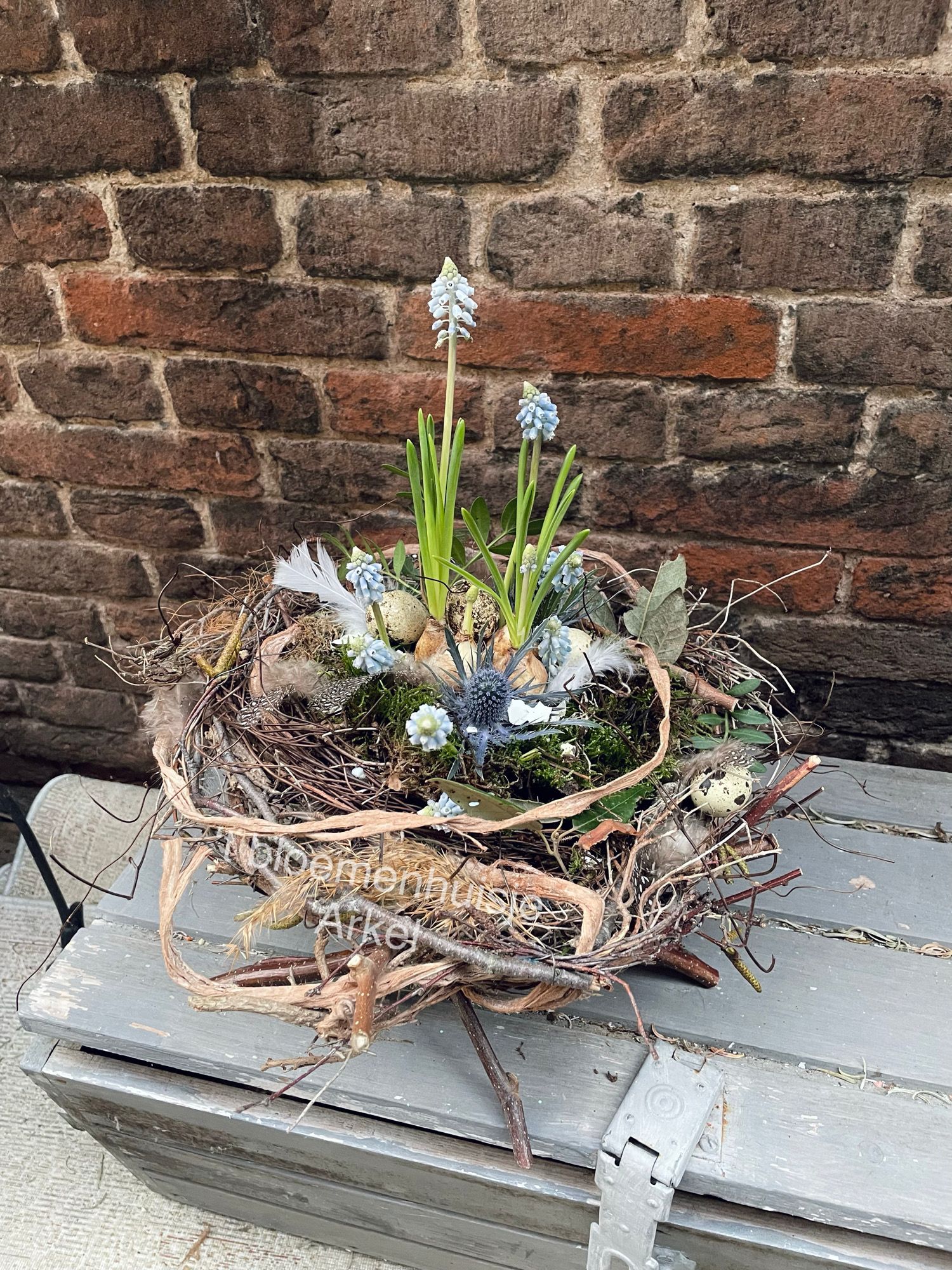 foto van bloemstuk met takken en eitjes en blauwe bloemen