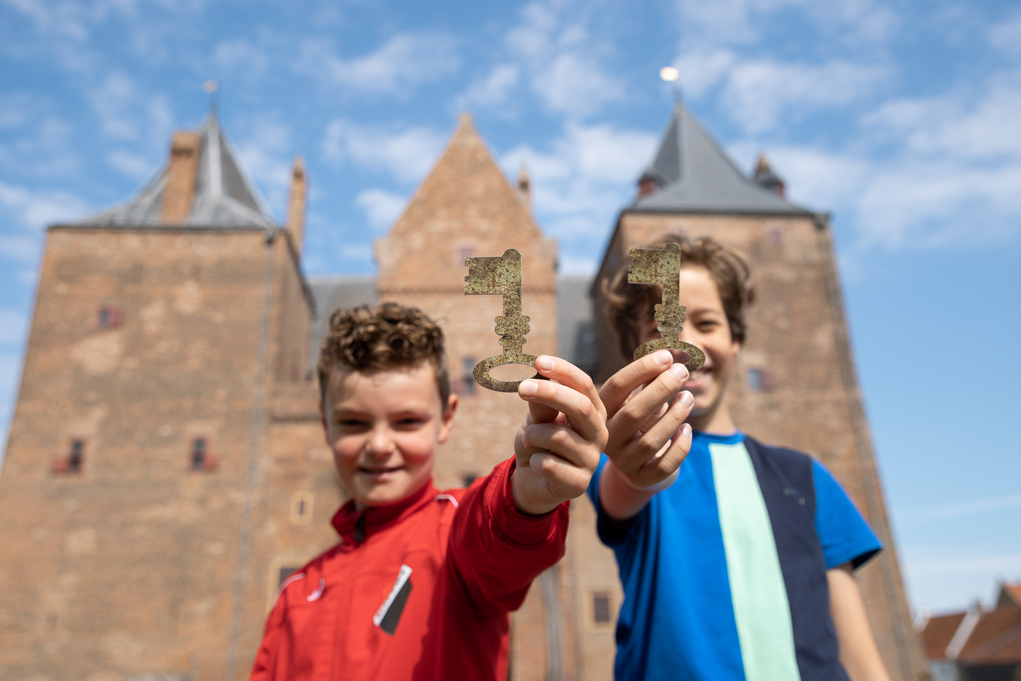 Twee jongens met de sleutel tot de toegangspoort van Slot Loevestein.