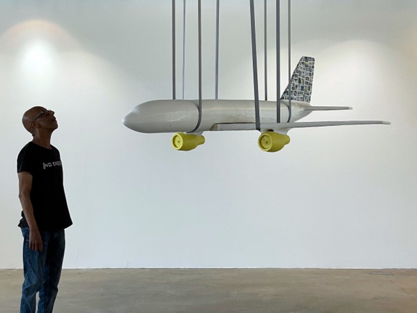 Foto van kunstwerk van vliegtuig met een persoon die ernaar kijkt.