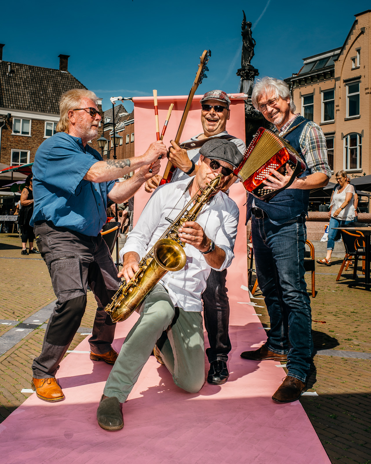 Vier mannen bespelen een instrument op de Grote Markt.