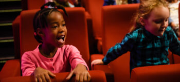 Foto van kinderen in de bioscoop zitten op rode stoelen