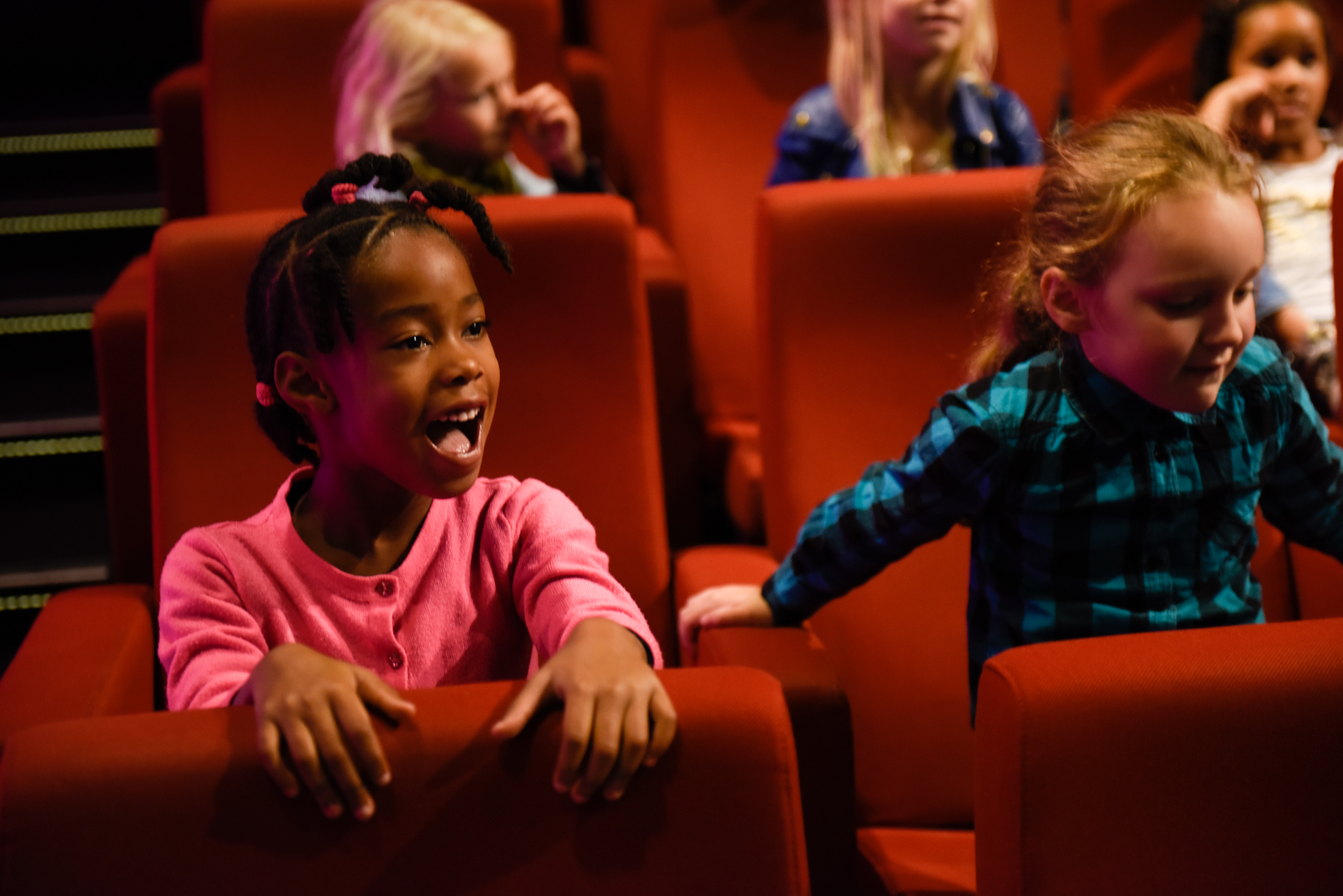 Foto van kinderen in de bioscoop zitten op rode stoelen